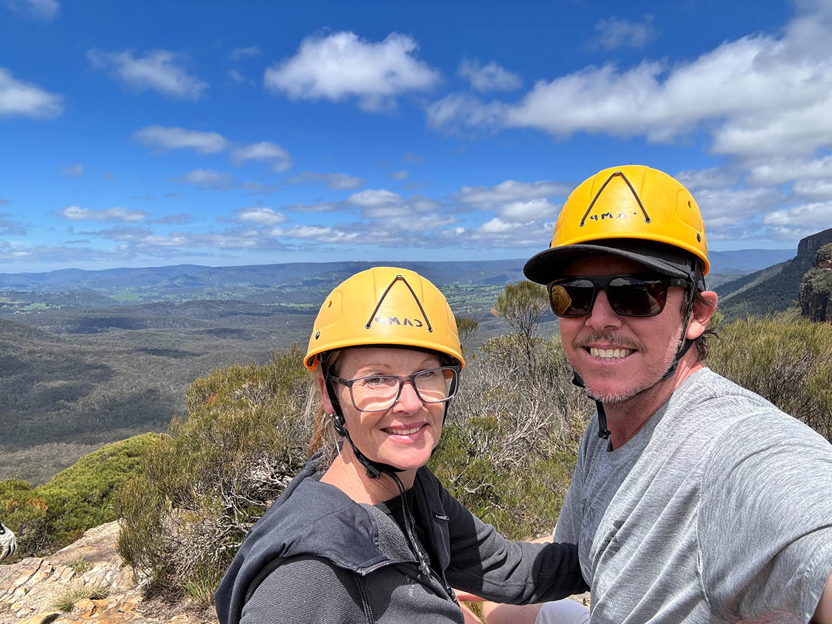 Brett & Julie with yellow hard hats ready to abseil over a ledge at the Blue Mountains.